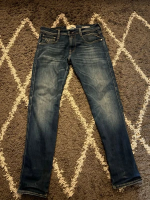 Blå slim fit jeans från replay  - Snygga blå slim fit jeans från Levi's med klassisk femficksdesign och slitningar på låren för en cool look. Jeansen har normal midja, dragkedjegylf och Levi's ikoniska läderpatch bak i midjan. Perfekta till en avslappnad streetstyle.