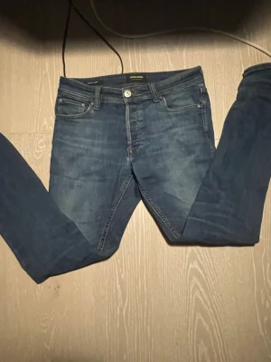 Mörkblå slim fit jeans Jack & Jones - Snygga mörkblå slim fit jeans från Jack & Jones med klassisk femficksdesign och läderpatch bak i midjan. Jeansen har en lätt tvättad look och raka ben. Perfekta för en trendig och avslappnad stil.