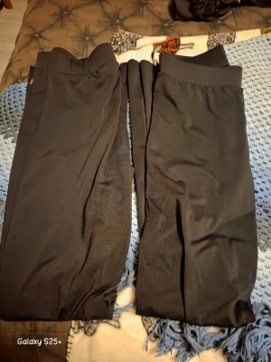 Gymnastik byxor - Säljer ett par svarta leggings med ribbad struktur och bred resår i midjan. De är stretchiga och sitter tight, perfekta till en avslappnad stil. Materialet känns mjukt och följsamt. Inga synliga loggor eller märken.