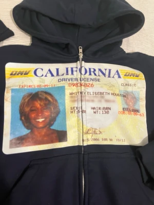 Mörkblå hoodie med WH id-tryck - Säljer en mörkblå hoodie med dragkedja och stor huva. På framsidan finns ett stort, färgglatt tryck av WH körkort som täcker bröstet. Hoodien har ribbade muddar och är tillverkad i mjukt 100% french terry bomull. Perfekt för dig som vill sticka ut med en unik design.