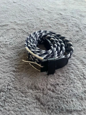 Randigt flätat bälte  - Snyggt svartvitt flätat bälte med silverfärgat spänne och detaljer i svart skinn. Perfekt accessoar för att lyfta din outfit med en snygg och trendig touch. Hör av dig vid intresse eller om du har några funderingar 🙌