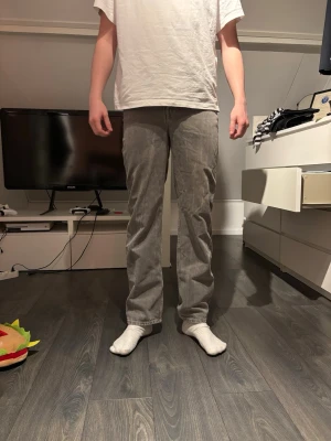 Grå raka jeans weekday - Säljer ett par grå jeans med rak passform och klassisk femficksdesign. Jeansen har normal midja och är tillverkade i ett mjukt denimtyg som ger en avslappnad look. Perfekta för dig som gillar en enkel och stilren stil.