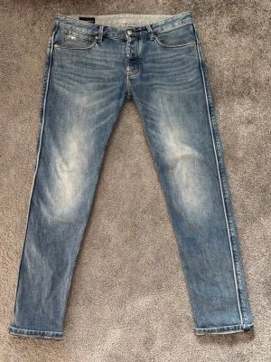 Emporio Armani-Jeans Blå Strl: W30 - Säljer mina riktigt snygga Emporio Armani-jeans i ljusblå washed material med naturliga slitningar. Jeansens mellan-ljusblå färg, tillsammans med de lite mörkare detaljer vid sömmarna gör så att jeansen passar bra till många outfits💫😍  Ordinarie pris: 2 600 Produkten finns även på annan plattform- först till kvarn som gäller😉  Tveka inte över att skriva vid frågor eller funderingar😁