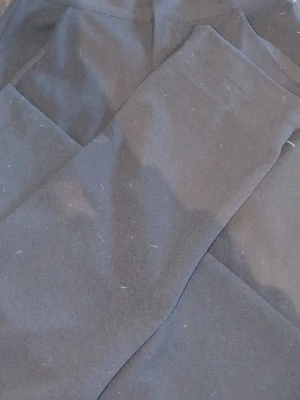 Svarta raka kostymbyxor - Säljer ett par klassiska svarta kostymbyxor med rak passform. Byxorna har en stilren look och är tillverkade i ett slätt tyg som känns dressat och passar perfekt till en snygg outfit. Inga synliga detaljer eller mönster.