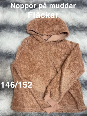  fluffig hoodie med huva - Mysig hoodie i fluffigt teddy-material med huva och långa ärmar. Hoodien har ribbade muddar och en avslappnad passform. Perfekt för dig som gillar en chill och bekväm stil.🌸 Noppor, fläckar. Storlek 146/152