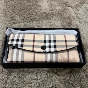 Beige plånbok med rutigt mönster - Snygg beige plånbok med klassiskt rutigt mönster i svart, vitt och rött. Plånboken har en avlång form och stängs med en svart knapp. Perfekt för dig som gillar stilrena accessoarer med en tidlös design.