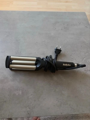 BaByliss vågtång för håret - Säljer en BaByliss vågtång med tre cylindrar i silverfärgat metall och svart handtag. Perfekt för att skapa snygga beach waves. Sladd med EU-kontakt medföljer. Enkel att använda och ger ett proffsigt resultat.