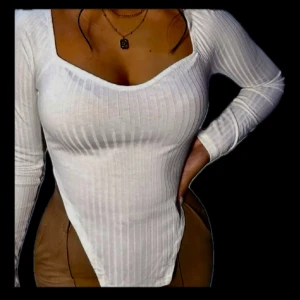 Vit ribbad långärmad tröja  - Säljer en vit ribbad tröja  med lång ärm och fyrkantig urringning. Sitter tight och har en stilren look som passar perfekt till både jeans och kjol. Superenkel att styla med smycken eller lager på lager.