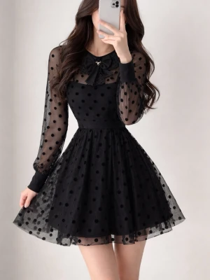 Elegant svart klänning med prickig mesh - Supersöt svart kortklänning med transparenta meshärmar och prickigt mönster. Klänningen har en fin rosettdetalj vid halsen, markerad midja och vippig kjol. Perfekt för dig som vill ha en lekfull och trendig look.
