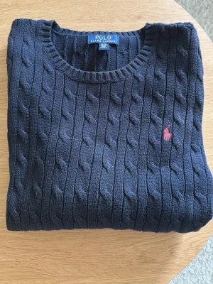 Mörkblå kabelstickad tröja Polo Ralph Lauren - Snygg mörkblå kabelstickad tröja från Polo Ralph Lauren med rund halsringning.