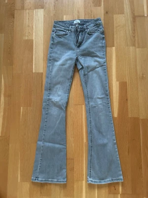 Grå flared jeans från Only - Säljer ett par grå flared jeans från Only. Jeansen har klassisk femficksmodell, normal midja och utsvängda ben. Materialet är mjukt denim med lite stretch för extra komfort. Perfekta för dig som gillar en retroinspirerad look.