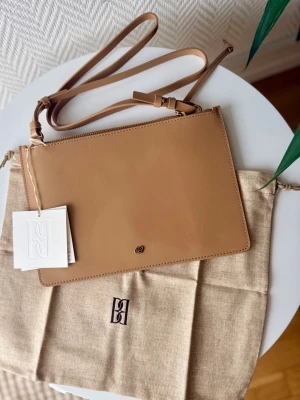 By Malene Birger Aya Leather Purse - Sand.  - Helt ny med lappar och dustbag enligt bilder!  Tillverkad i återvunnen läder.   Juster- och avtagbar axelrem.  Färg: Sand  Nypris 1799kr