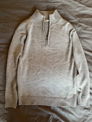 Grå stickad tröja med halvzip - Säljer en stilren grå stickad tröja med halvzip och hög krage. 