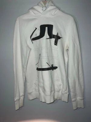 J Lindeberg hoodie  - Väldigt snygg J Lindeberg hoodie. Hoodien har tryck på framsidan i form av J Lindeberg loggan och i text. Hoodien har några små missfärgningar på armarna som man måste kolla noggrant för att se annars väldigt bra skick. Perfekt för dig som vill ha en skön och snygg hoodie! Priset är inte hugget i sten.