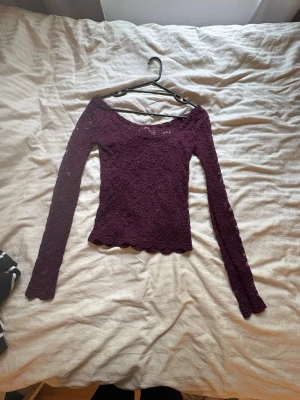 Mörklila/vinröd spetsblus med lång ärm - Säljer en mörklila/vinröd blus med lång ärm och snygg spetsdesign över hela. Med urringad krage och fin design längst ner på det och på ärmarna. Fint nu till våren och sommaren, Är i väldigt bra skick, har aldrig använt💕frakt ingår och det är 35kr