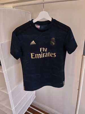 Real Madrid tröja  - Säljer denna riktigt snygga Real Madrid tröja med Eden Hazard på ryggen. Den är knappt använd och i riktigt bra skick. Den är i barnstorlek 11-12 år. 