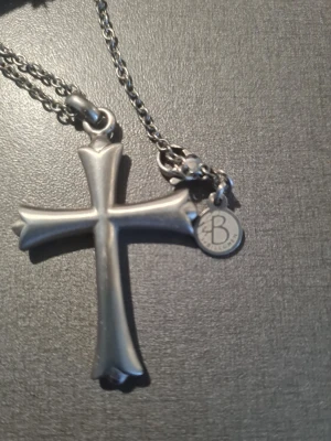 Silverfärgat korshalsband från Baller - Snyggt halsband i silverfärg med ett stort kors som hänge. Kedjan är av metall och har en liten rund bricka med Baller-loggan. Korset har mjuka, rundade kanter och en stilren design som sticker ut.
