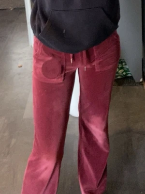 Vinröda velourbyxor Juicy Couture - Säljer ett par vinröda mjukisbyxor från Juicy Couture inte jätte använda, inga större synliga tecken på användning, super fina. Storlek xxs och jag är 166 och dom går ner till mina hälar, passar även xs/s. Kan sänka priset vid snabb affär 