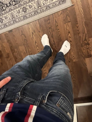Mörkblå slim fit jeans - Säljer ett par mörkblå slim fit jeans med klassisk femficksdesign och snygga slitningar. Jeansen har en modern passform och är perfekta för en avslappnad stil. Materialet är denim med stretch för extra komfort.