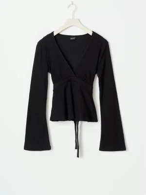 Svart blus - Trendig svart blus från Gina Tricot med långa ärmar och knytband på ryggen. Toppen har en djup v-ringning och lätt utsvängda ärmslut. 