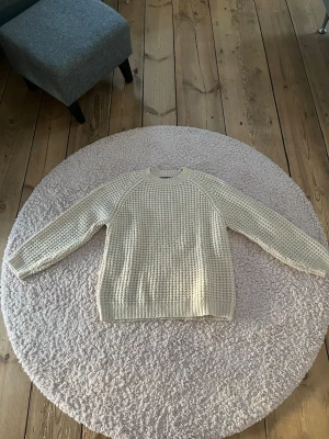 Beige stickad tröja med grov struktur - Säljer en beige stickad tröja med grov, rutmönstrad struktur. Tröjan har rund halsringning, långa ärmar och ribbade muddar vid ärmslut och nederkant. Perfekt för lager-på-lager och enkel att matcha med jeans eller kjol.