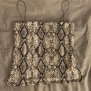 Ormmönstrad linnetopp med tunna band - Oanvänd. Toppen har tunna axelband och är figurnära. Perfekt för att lyfta vilken outfit som helst. 