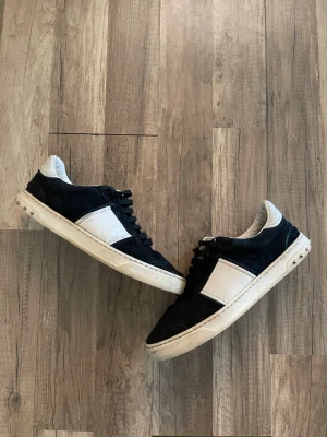 Valentino flycrew - Snygga sneakers i svart och vitt med klassisk låg profil. Skorna har svarta mockadetaljer, vita partier på sidan och vit sula. Svarta skosnören och vadderad insida för extra komfort. Perfekta för en avslappnad streetwear-look.skyddsula under för att de ska hålla längre 