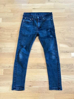 Mörkblå Levi's skinny jeans - Snygga mörkblå skinny jeans från Levi's med klassiska fem fickor och röda sömmar vid bakfickan. Jeansen har lätt slitna detaljer på benen och är tillverkade i denim med stretch för en bekväm passform.