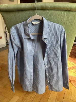 Blåvit randig skjorta med knappar - Blåvit randig skjorta från H&M. Storlek 146.