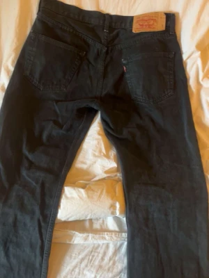 Svarta Levi's jeans/h&m jeans - Svarta jeans från Levi's med klassisk femficksdesign och raka ben. Jeansen har en läderpatch bak i midjan. Och ljusblå Jeans från H&M.De är tillverkade i bomull. Både jeans är i storlek 33/32 