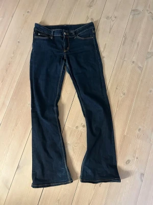 Mörkblå bootcut jeans - Snygga mörkblå bootcut jeans med klassiska fem fickor och kontrastsömmar. De passar mig sol brukar ha en mindre storlek i midjan, en defekt på ena benet se sista bilden. Storlek 30/32