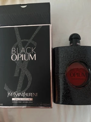 Yves Saint Laurent Black Opium 150ml - Black Opium Eau de Parfum från Yves Saint Laurent i en snygg svart glittrig flaska med rund röd detalj i mitten. Parfymen kommer i originalkartong och rymmer 150 ml. En ikonisk doft med lyxig och modern design. Aldrig använd endast test sprutad🫶🏽