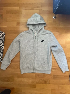 Grå hoodie från Comme des Garçons - Sällsynt grå zip-hoodie från CDG play. Storlek S. Den är i fint skick och har inga större defekter. Perfekt på nu på våren eller till kyliga sommarkvällar. Priset kan diskuteras vid snabb affär. Tveka inte att skriva om ni har några frågor/funderingar. 