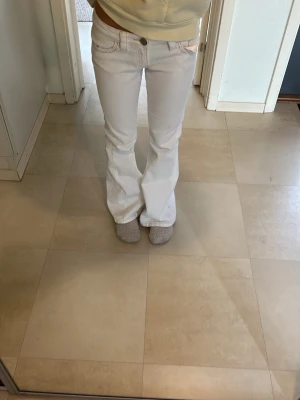 Vita bootcut jeans med fickdetaljer - Säljer ett par vita bootcut jeans med snygga fickdetaljer bak och klassisk femficksmodell. Jeansen har låg midja och är tillverkade i ett mjukt bomullsmaterial med lite stretch. Perfekta för dig som gillar en clean och fräsch look.