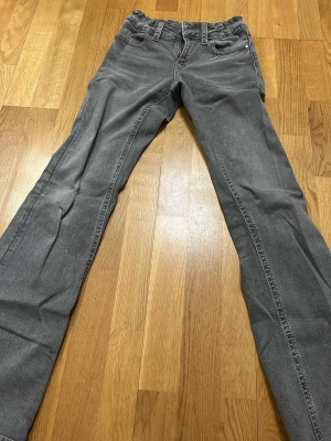 Grå jeans från Gina  - Snygga grå jeans med klassisk bootcut och lowasted. Jeansen har silverfärgade nitar och normalhög midja. Perfekta för en avslappnad och trendig look. Materialet är mjukt denim som ger en skön känsla hela dagen.
