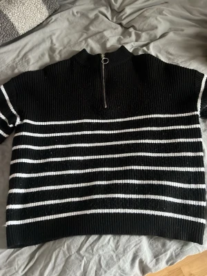 Svartvitrandig stickad tröja Shein - Stickad tröja från Shein i svart med vita horisontella ränder. Tröjan har halv hög krage och dragkedja framtill.
