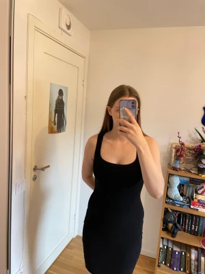 Svart tight klänning - Klänning som har en enkel och stilren design, sitter figurnära och slutar ovanför knäna. Utmärkt för dig som gillar den minimalistisk stilen.