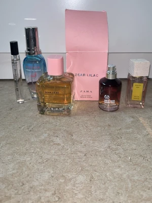 Parfymset med olika dofter från Zara m.fl. - Ett parfymset med fem olika dofter: Zara Dear Lilac i fyrkantig glasflaska med rosa lock och ask, The Body Shop White Musk i rund mörk flaska med silverdetaljer, & Other Stories Palermo Viola i rektangulär flaska med vit kork, samt två mindre flaskor inklusive en blå och en genomskinlig. Säljer allt ihop för priset 💕