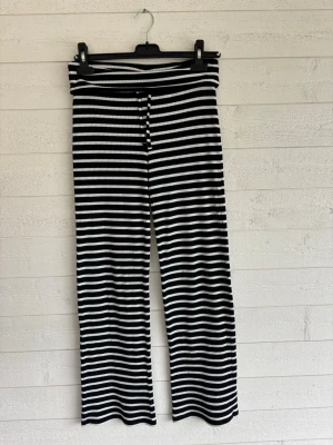 Randiga ribbade mjukisbyxor  - Svartvita mjukisbyxor med ränder och ribbad struktur. Snörning i midjan med nedvikt kant. Stretchigt och mjukt material som är väldigt bekvämt.