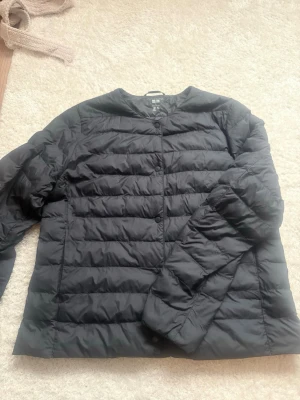 Svart pufferjacka från Uniqlo - Säljer en svart pufferjacka från Uniqlo med PUFFERTECH-teknologi. Jackan har rund halsringning, tryckknappar framtill och är tillverkad i ett lätt och slitstarkt material. Perfekt för kalla dagar och enkel att matcha med olika outfits. Köptes för 700kr och är inte använd mycket alls. Passar främst S-M men även L eftersom liten i storlek (pris kan diskuteras)