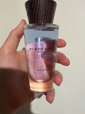 Burberry Touch For Men EdT 100ml - Burberry Touch For Men Eau de Toilette i en stilren glasflaska med träliknande lock. Flaskan rymmer 100 ml och har en transparent design med svagt rosa och blå toner. En klassisk herrdoft som känns både fräsch och maskulin.