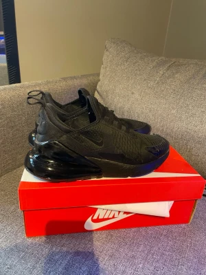 Nike Air Max 270 Triple Black sneakers - Snygga Nike Air Max 270 Triple Black sneakers i helsvart färg. Två pytte små knappt hål längst i fram som ni ser men har man svarta strumpor eller syr igen lite snabbt hemma syns inget. Hällen är hel och i mycket fint skick. Priset kan diskuteras vid snabb affär.