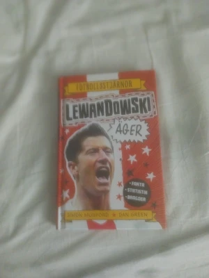 Lewandowski äger - Fotbollsstjärnor - En färgstark bok om fotbollsstjärnan Lewandowski, skriven av Simon Mugford och illustrerad av Dan Green. Boken är röd och vit med coola illustrationer, fylld med fakta, statistik och bragder om Lewandowskis karriär. Perfekt för dig som älskar fotboll och vill veta mer om en av världens bästa anfallare.