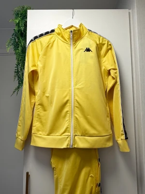 Elegant Kappa Pyjamas-set - Superfin pyjamas i ljust färg, med sidoöppningar med knappar – kan öppnas helt eller delvis för en stilren look.  Använd endast några gånger, i nästan nyskick. Perfekt för mysiga kvällar eller stilfull hemmakänsla.