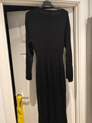 Svart långärmad ribbad klänning - En svart långklänning med lång ärm och rund halsringning. Klänningen är ribbad vilket ger en snygg struktur och sitter figurnära. Perfekt för dig som gillar en stilren och enkel look.