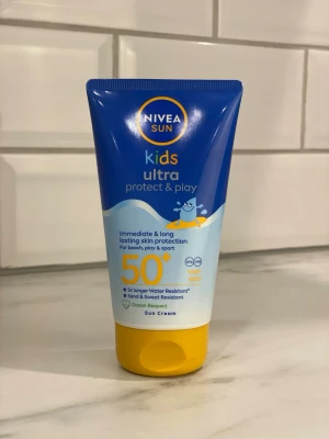 NIVEA Sun Kids Ultra SPF 50+ solkräm - NIVEA Sun Kids Ultra Protect & Play solkräm med SPF 50+ ger omedelbart och långvarigt skydd mot solen. Tuben är blå och gul, innehåller 150 ml och är speciellt framtagen för barn. Vatten-, sand- och svettresistent formula.