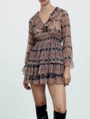 Mönstrad kortklänning  - Bohemisk kortklänning från Zara med blommigt mönster i vinröda, blå och beige toner. Klänningen har lång ärm med volang vid ärmslut, rundad halsringning och lätt rynkad midja. 