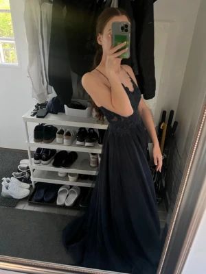 Marinblå balklänning med spetsdetaljer - Elegant marinblå långklänning med tunna axelband och v-ringad spets upptill. Klänningen passar perfekt för bal eller festliga tillfällen! Klänningen är använd endast en gång och är i nyskick. Klänningen är köpt på JJ’s house för 2132kr. Kan mötas upp i nästan hela stockholms området och klänningen finns i Täby men jag fraktar ej. Pris kan diskuteras!