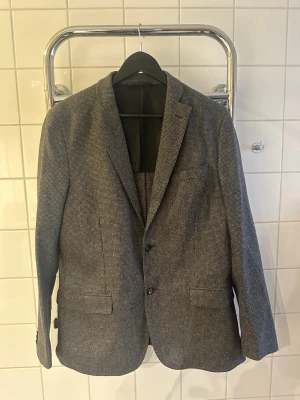 J.Lindeberg kavaj - Säljer en grå J.Lindeberg kavaj i bra skick, storlek 50. Kavajen är slim fit och sitter bra på kroppen.