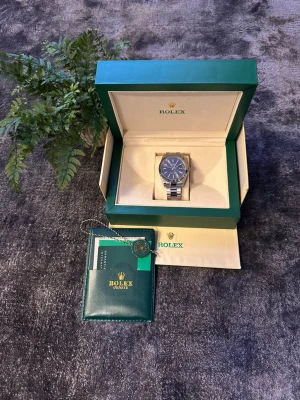 Role Datejust 41mm Dark Gray Dial / Oyster Steel - Snygg Role Oyster Perpetual Datejust med mörkgrå urtavla och räfflad bezel i stål. Klockan har elegant mörkgrå tavla med ljusa index, datumfönster på 3 och robust Oyster-länk i rostfritt stål. Klassisk och exklusiv design med fluted bezel som ger en sofistikerad touch. Automatic movement. Dial size 41mm. Quick deal with serious buyers. Fast shipping.